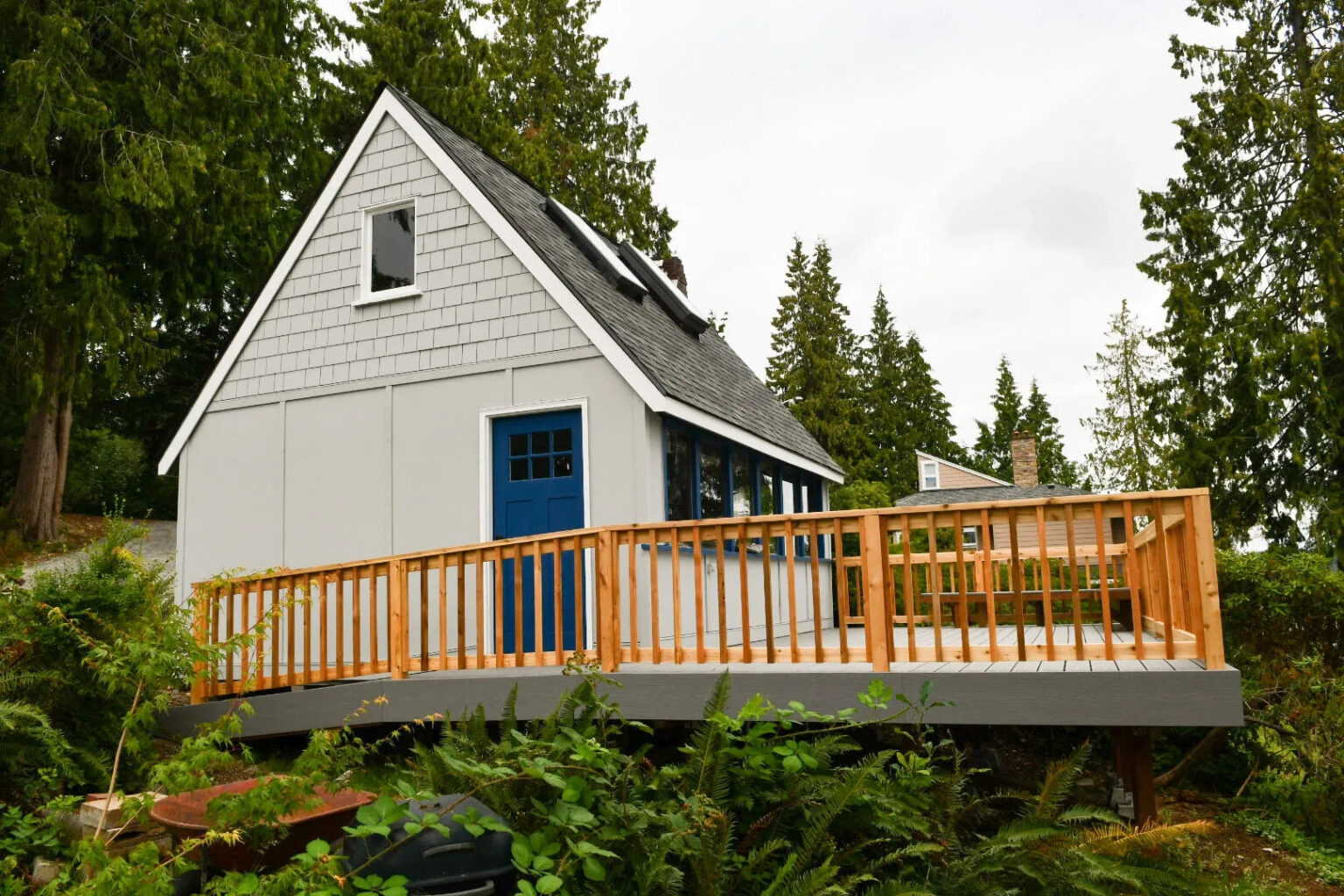 exterior view of dry cabin surrounded by evergreens and a custom wood deck.