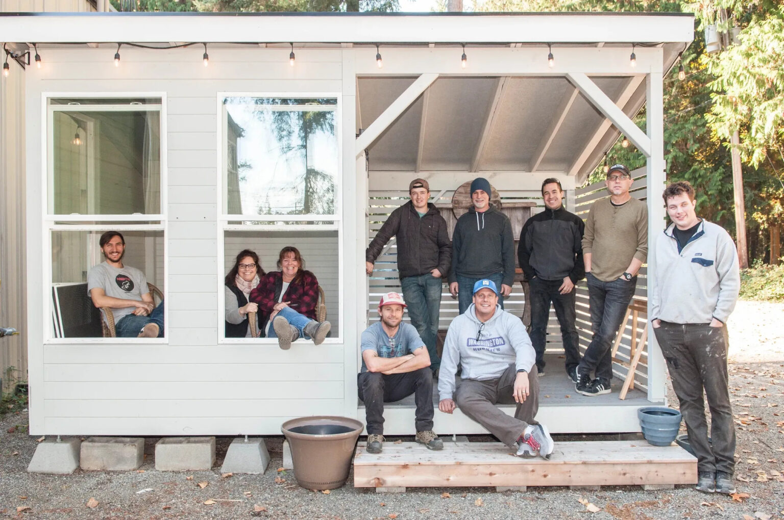 group of people posing inside of tiny house/she shed. construction team.