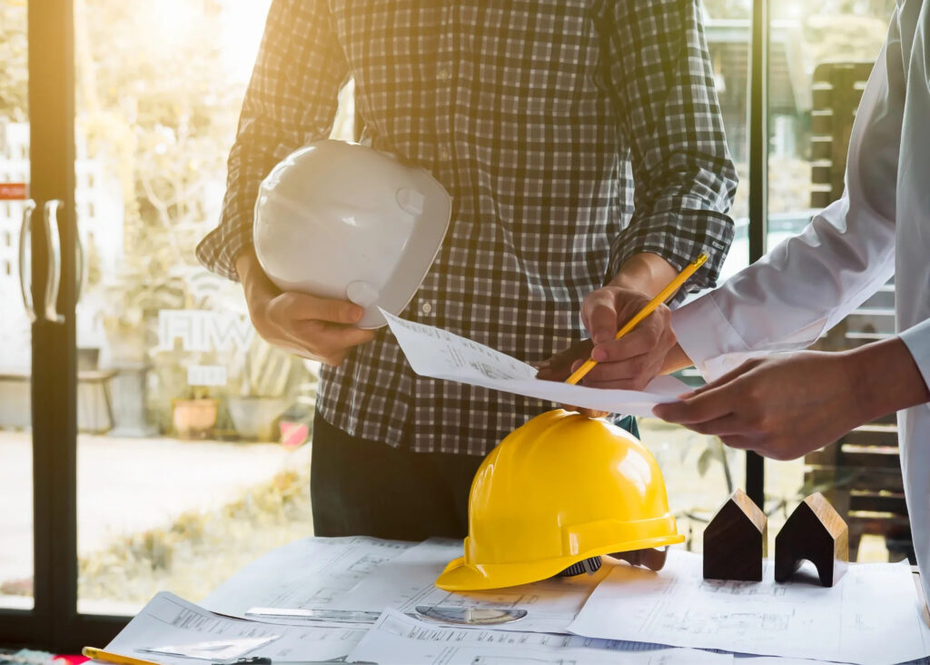 image of two people with architectural plans and hard hats