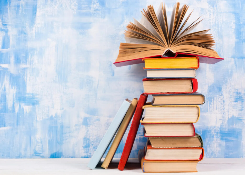 stack of colorful books against a blue wall